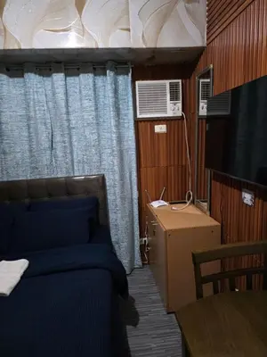 a bedroom with a bed and a table and a window at nicecondotel in Manila