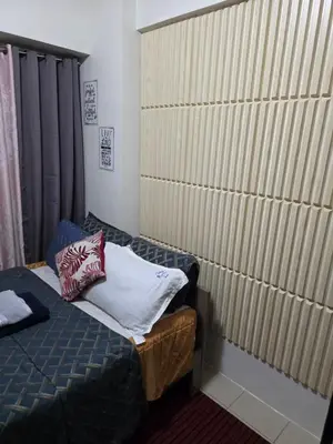 a small room with a bed and a large wall at nicecondotel in Manila