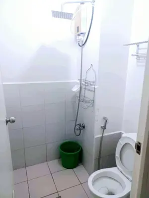 a bathroom with a toilet and a green bucket at Staycation Condotel Urban Deca Tower Edsa Mandaluyong in Manila