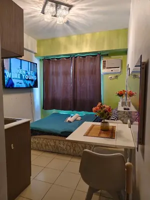 a room with a bed with a tv and a table at Staycation Condotel Urban Deca Tower Edsa Mandaluyong in Manila