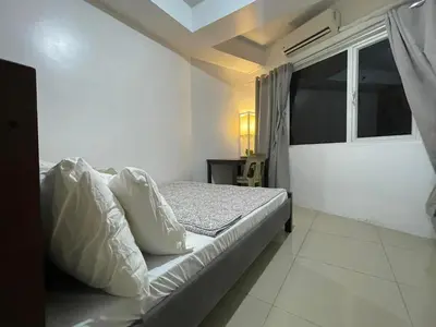 a white bedroom with a bed and a window at Spacious One Bedroom Unit in MOA in Manila
