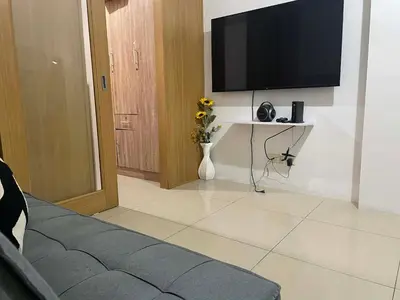 a living room with a flat screen tv on a wall at Spacious One Bedroom Unit in MOA in Manila