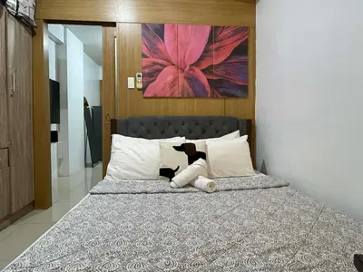a bed with a black and white cat laying on it at Spacious One Bedroom Unit in MOA in Manila