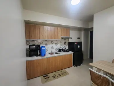 a kitchen with wooden cabinets and a black refrigerator at Chic Getaway in Sucat in Manila