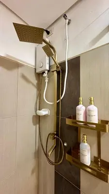 a shower in a bathroom with three soap bottles at Warm & Homey Staycation Suite in Manila