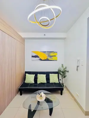 a living room with a black couch and a chandelier at 1 Bedroom Unit near MOA & NAIA Terminal in Manila