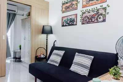 a black couch in a living room with pictures on the wall at Shore Residence Tower A w Pool Near Airport and MOA in Manila