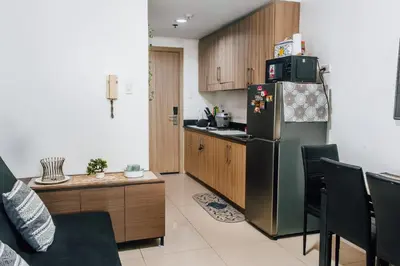 a kitchen with a stainless steel refrigerator and wooden cabinets at Shore Residence Tower A w Pool Near Airport and MOA in Manila