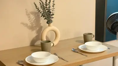 a table with two cups and a vase on it at Cozy Studio in Salcedo Village Makati City in Manila