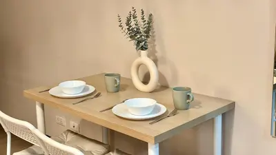 a wooden table with plates and cups and a vase at Cozy Studio in Salcedo Village Makati City in Manila
