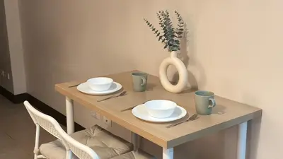 a wooden table with plates and cups and a vase at Cozy Studio in Salcedo Village Makati City in Manila