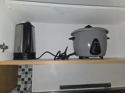 a slow cooker sitting on a shelf next to a toaster at J&W Homestay in Manila