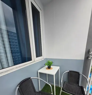 a balcony with two chairs and a table and two windows at J&W Homestay in Manila