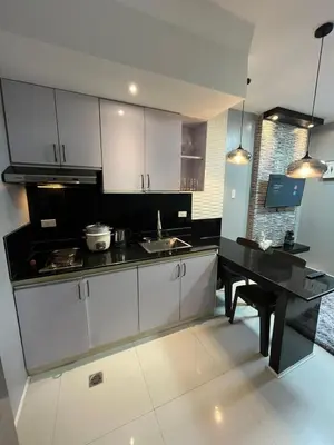 a kitchen with white cabinets and a black counter top at Antel Spa Residences 2602 in Manila