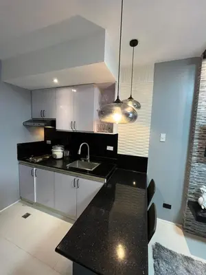 a kitchen with white cabinets and a black counter top at Antel Spa Residences 2602 in Manila