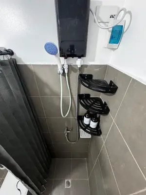 a shower in a bathroom with a phone and shoes at Modern Studio with Balcony and City View Near BGC in Manila