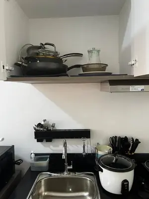 a kitchen with a sink and a shelf with pots and pans at Modern Studio with Balcony and City View Near BGC in Manila