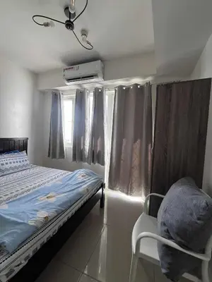 a bedroom with a bed and a chair and curtains at Two-Bedroom by Metro Staycation in Manila