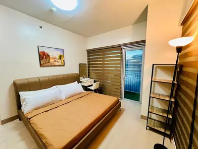 a bedroom with a bed and a desk and a window at 3BR Penthouse Suite Sunset View in front of Okada in Manila