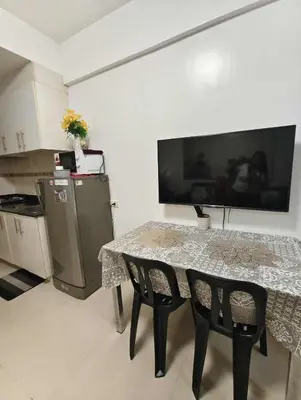 a kitchen with a table with two chairs and a tv on the wall at Sea Residence by una in Manila