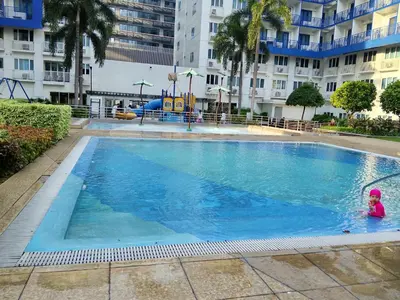a little girl swimming in a large swimming pool at Sea Residence by una in Manila
