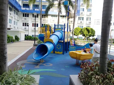 a boy playing on a playground in a park at Sea Residence by una in Manila