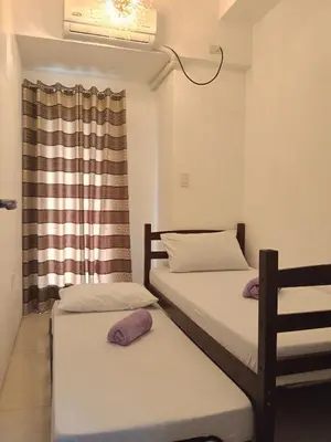 two beds in a room with a window at Stay Manila Hostel in Manila