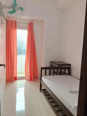 a bedroom with a bed and a window with a fan at Stay Manila Hostel in Manila