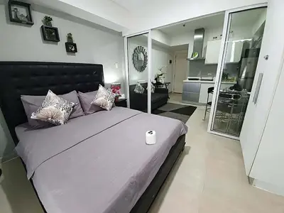 a bedroom with a large bed and a living room at Azure Urban Resort Residences in Manila