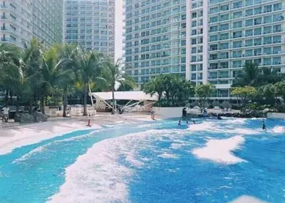 a large pool with blue water in front of tall buildings at Azure Urban Resort Residences in Manila