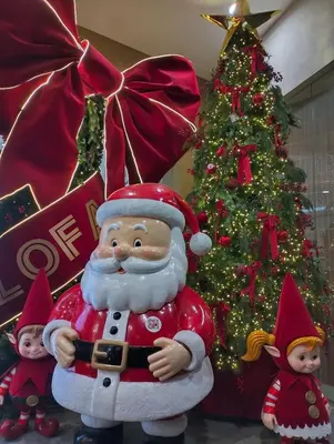 a santa claus statue next to a christmas tree at Little NOAH in Manila
