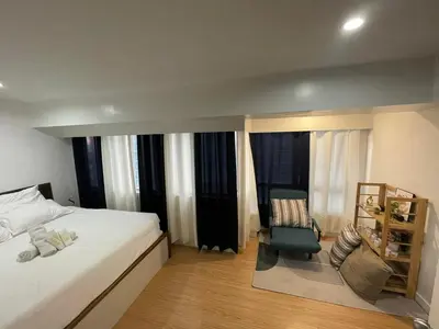 a bedroom with a bed and a chair and windows at PrimeStay BGC in Manila