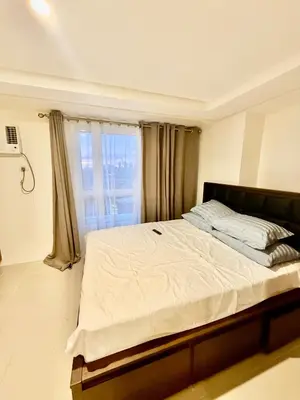 a bedroom with a large bed with a window at Stylish New Condo at Covent Garden Sta Mesa in Manila