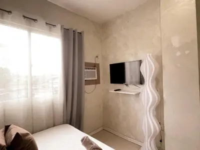 a bedroom with a bed and a tv and a window at Boho Scandinavian with free Netflix, Wifi & Parking in Dasmariñas