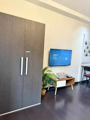 a living room with a large cabinet and a tv at The Gramercy Residences in Manila