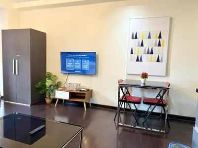 a living room with a glass table and a tv at The Gramercy Residences in Manila