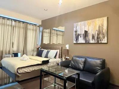a living room with a bed and a glass table at The Gramercy Residences in Manila