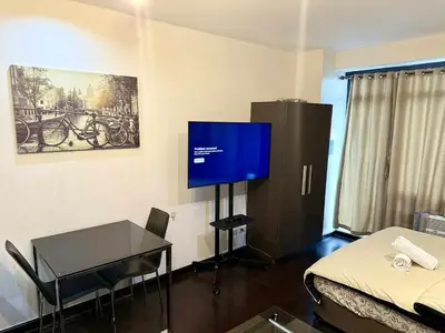 a room with a tv and a table and a bed at The Gramercy Residences in Manila