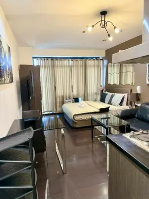 a hotel room with a bed and a living room at The Gramercy Residences in Manila