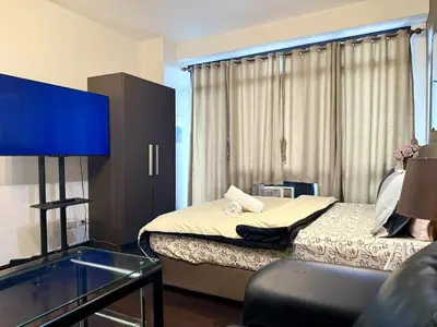 a hotel room with a bed and a tv in it at The Gramercy Residences in Manila
