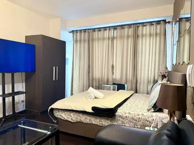 a hotel room with a bed and a flat screen tv at The Gramercy Residences in Manila