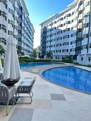 a pool with a chair and an umbrella next to a building at Family Oasis at Leaf with Netflix in Muntinlupa in Manila