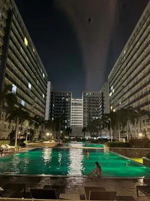 a person sitting in a swimming pool at night at Sea Residences By Jervis in Manila