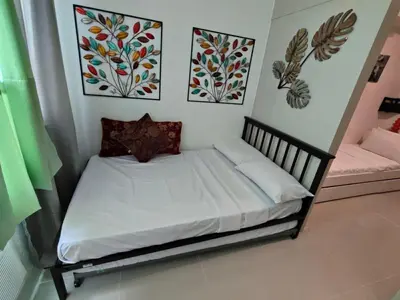 a small bed in a room with three pictures on the wall at Sea Residences By Jervis in Manila