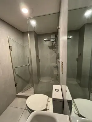 a bathroom with a shower and a toilet and a sink at Sunnyplace Residences Near NAIA Airport in Manila