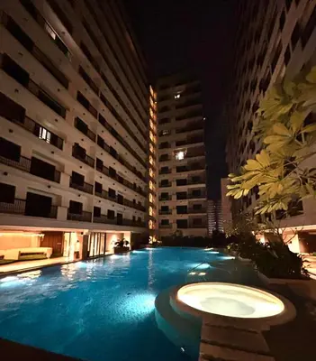 a large swimming pool at night with tall buildings at Sunnyplace Residences Near NAIA Airport in Manila