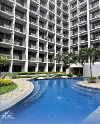 a swimming pool in front of a large building at Thrifty Comfy Luxe Stays in Manila