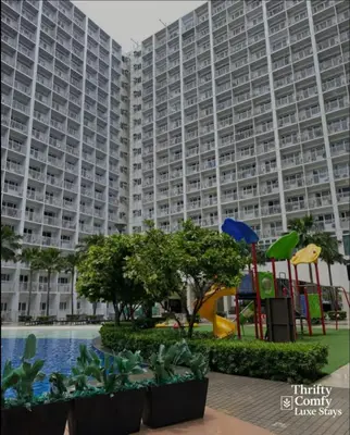 a large apartment building with a playground in front of it at Thrifty Comfy Luxe Stays in Manila