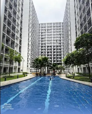 a large swimming pool in front of tall buildings at Thrifty Comfy Luxe Stays in Manila