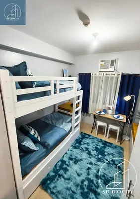 a bedroom with bunk beds and a table at Studio City Staycation in Manila